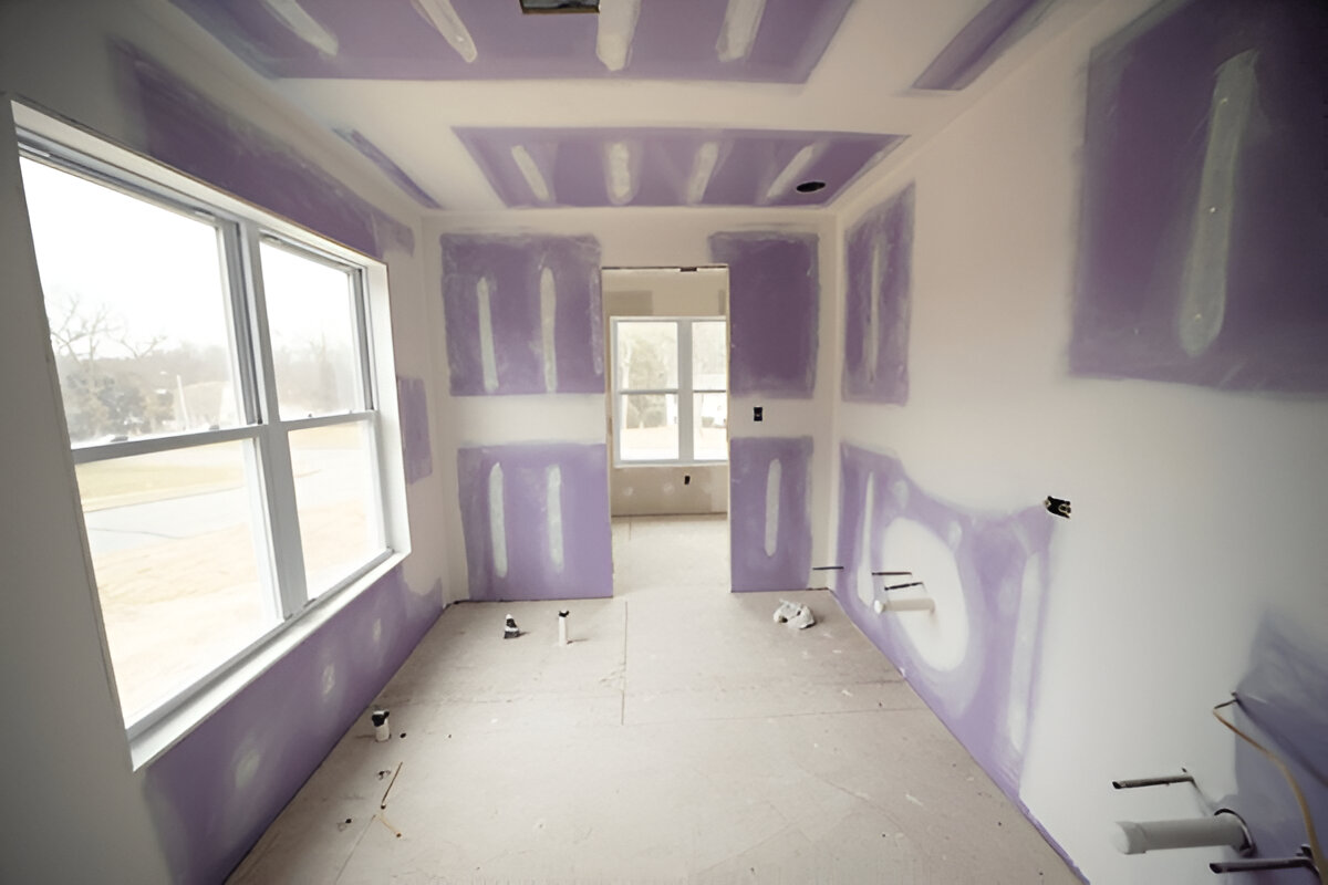 Room under construction with purple mold-resistant drywall and visible plumbing rough-ins on the floor and walls.