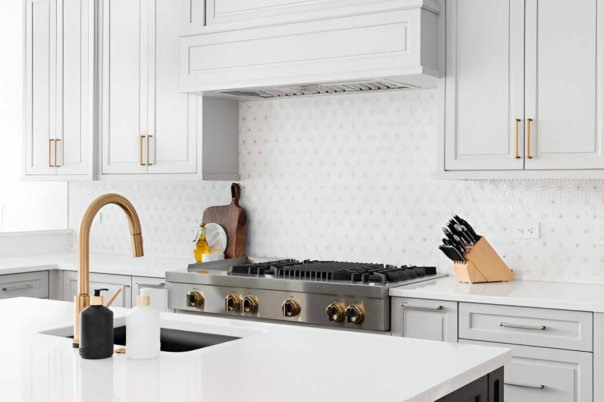 Elegant white kitchen with gold faucet and marble backsplash