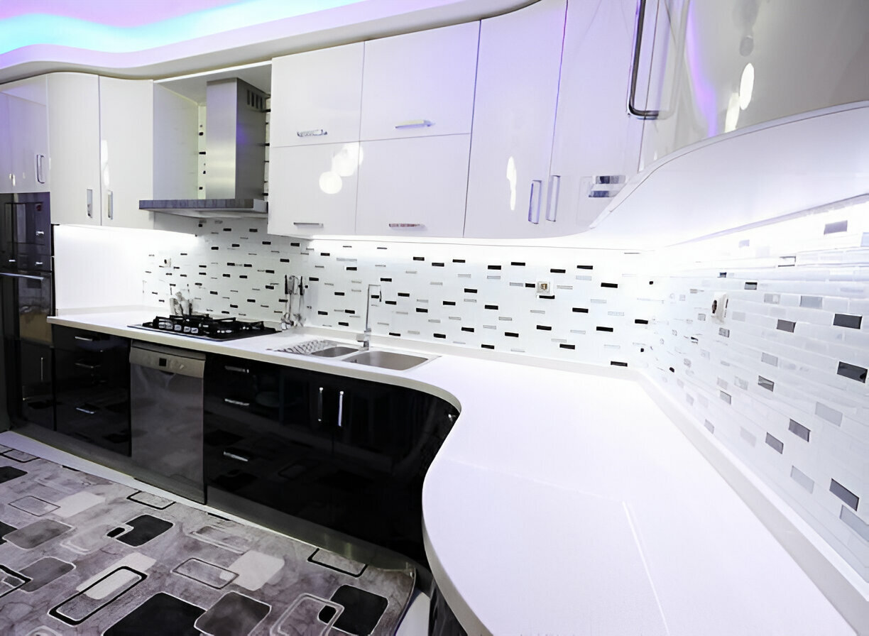 Contemporary kitchen with glossy white cabinets, black-and-white backsplash, and a curved countertop 