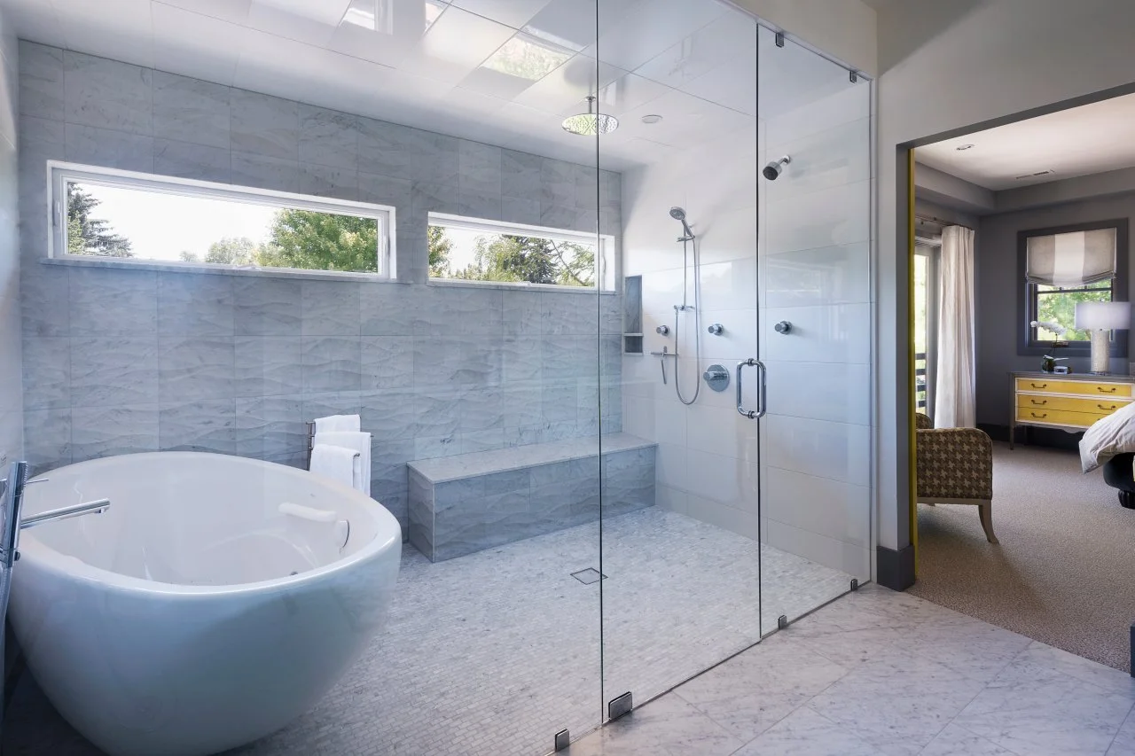 Large bathroom featuring a freestanding soaking tub, walk-in shower with bench, and natural light from horizontal windows