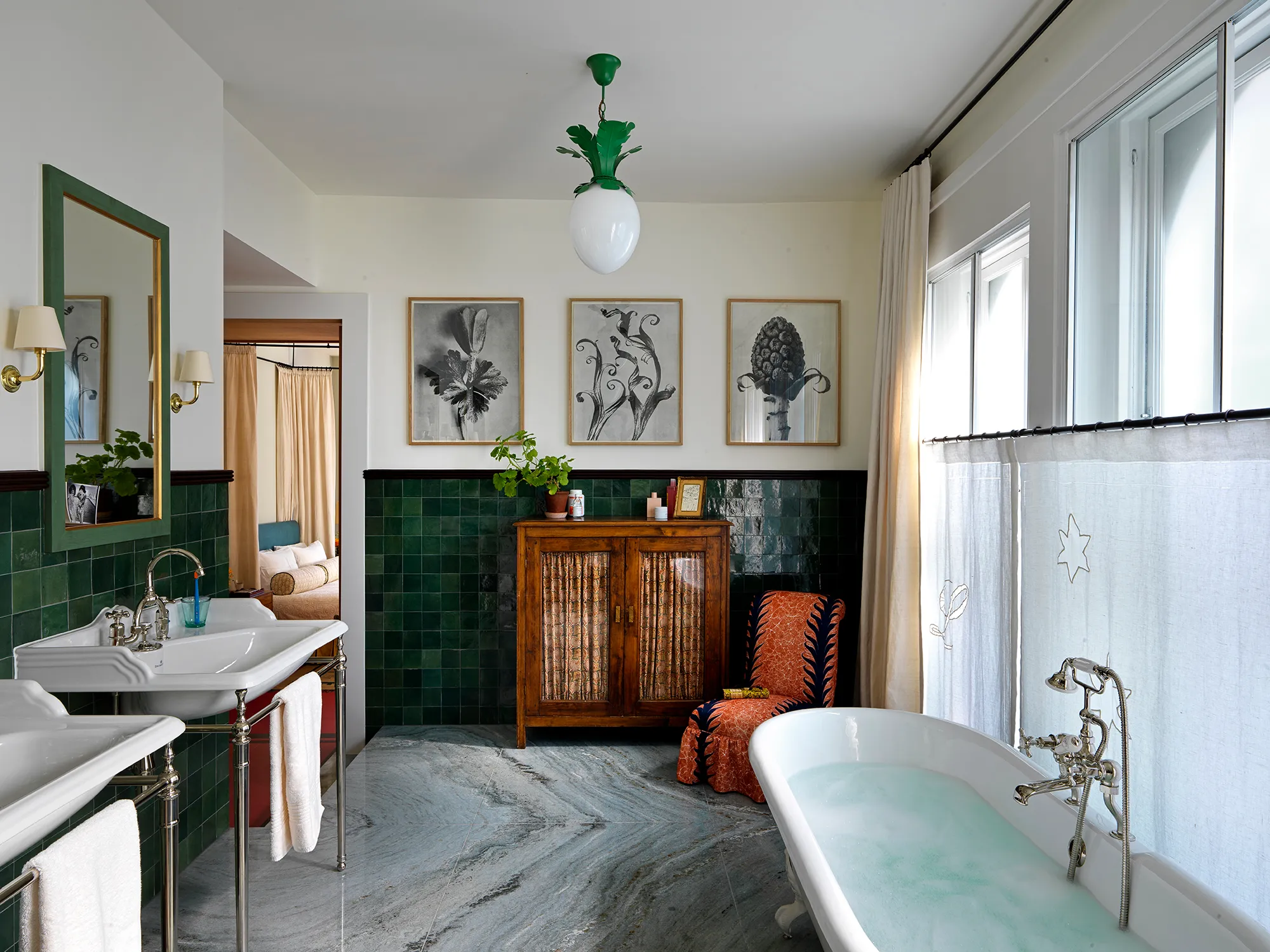 Elegant bathroom featuring green wall tiles, vintage wood cabinet, freestanding bathtub, and dual sinks