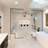 Bright modern bathroom featuring a walk-in glass shower, freestanding soaking tub, black matte fixtures, and marble-look tiles