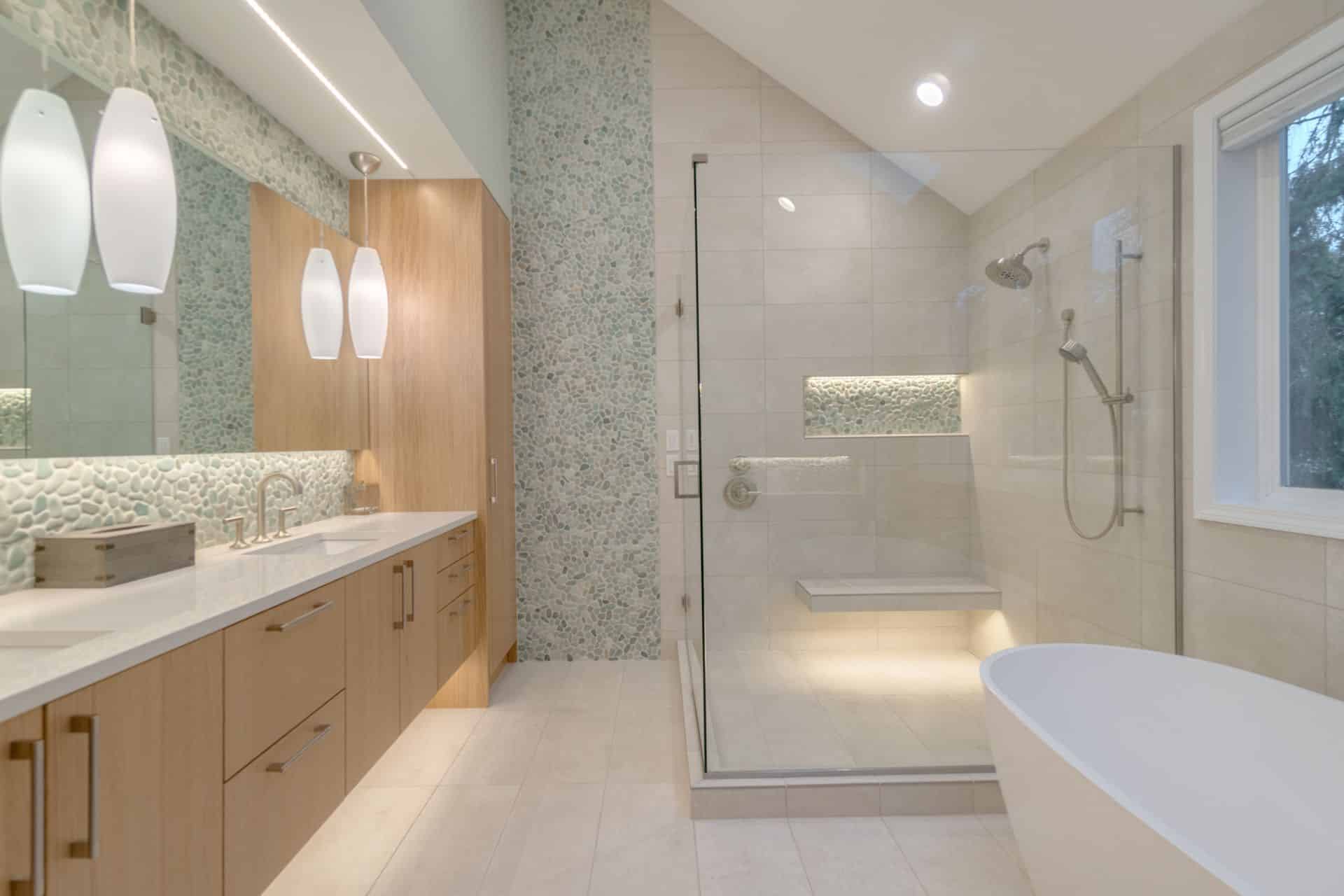 Contemporary bathroom with glass walk-in shower, freestanding bathtub, and pebble tile accent wall