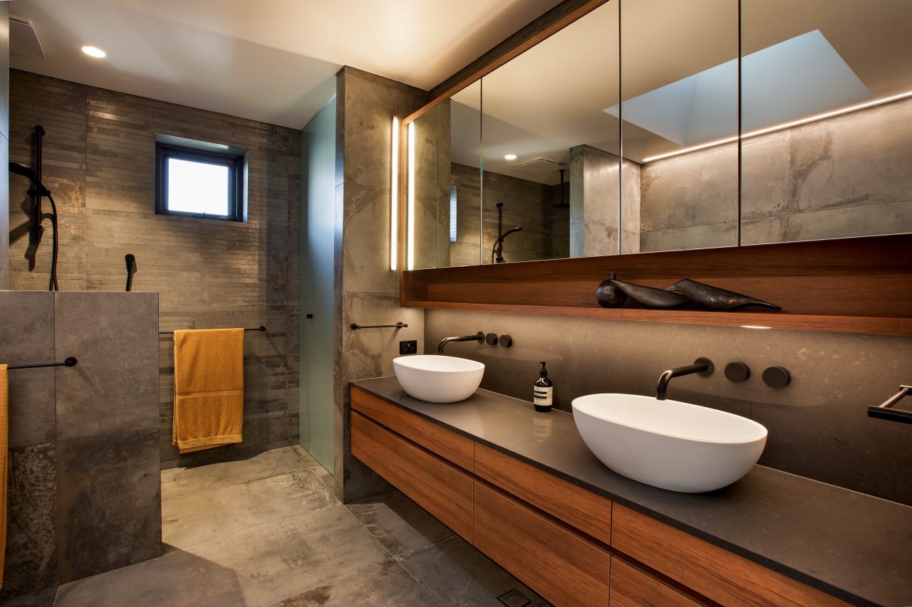 Contemporary bathroom featuring vessel sinks, wood cabinetry, concrete finishes, and black matte fixtures.