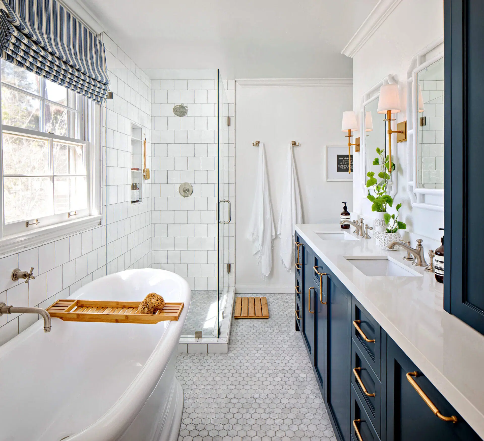 Bathroom with freestanding tub, glass shower, and navy vanity with gold hardware.