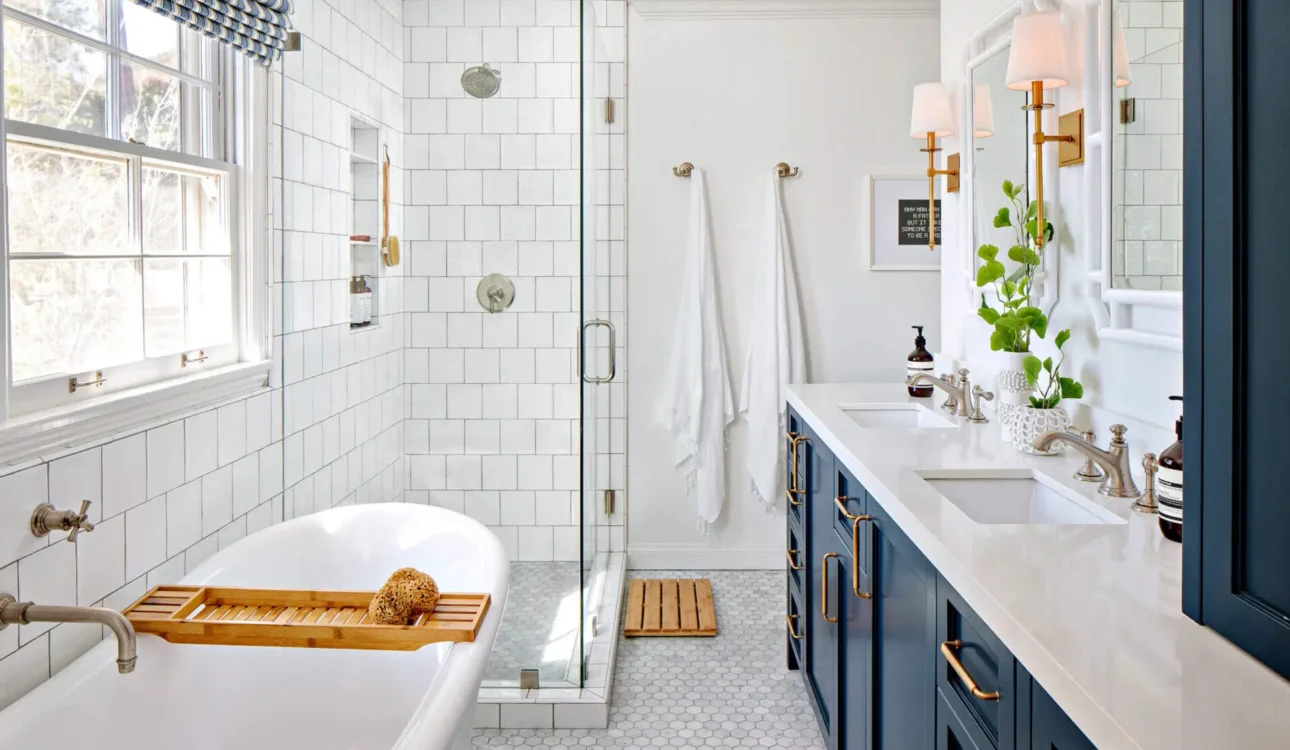 Classic bathroom with navy blue vanity, freestanding tub, and glass shower
