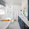 Classic bathroom with navy blue vanity, freestanding tub, and glass shower