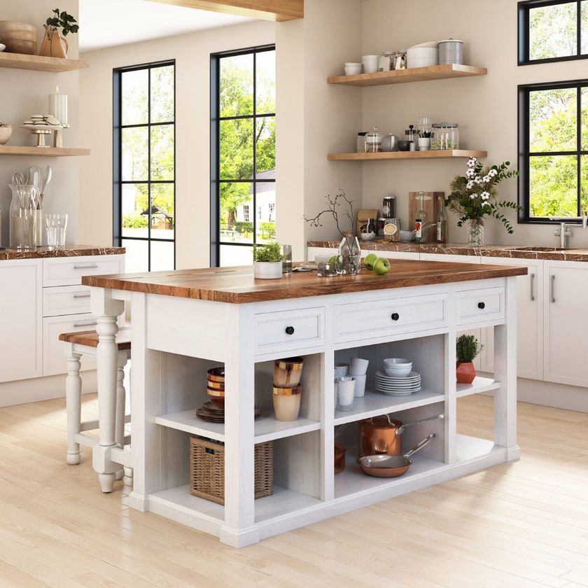 A bright farmhouse kitchen featuring a white kitchen island with a wooden countertop, open shelves displaying dishes and cookware, surrounded by large windows and natural light.