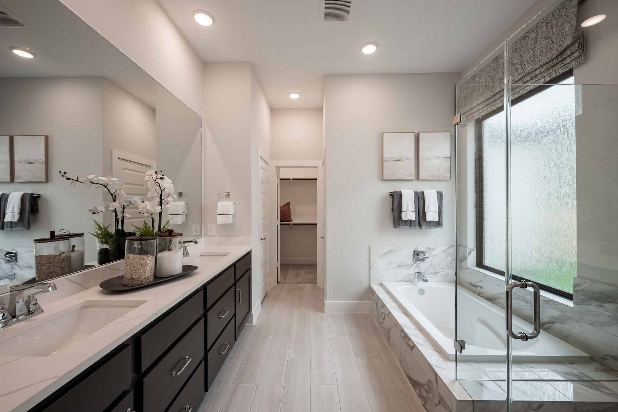 Modern bathroom with double vanity, glass shower, and built-in bathtub.
