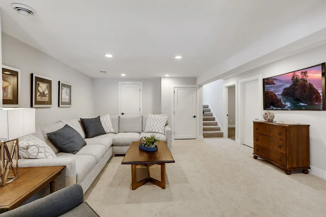 A cozy, well-lit finished basement with a sectional sofa, TV, and contemporary decor.