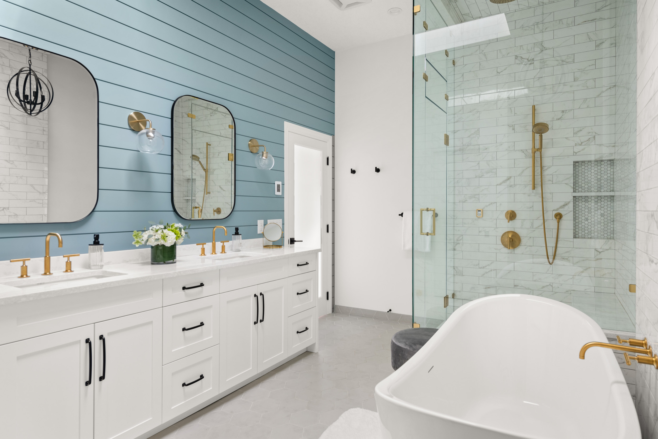 Bright bathroom with blue accent wall, white vanity, and glass shower