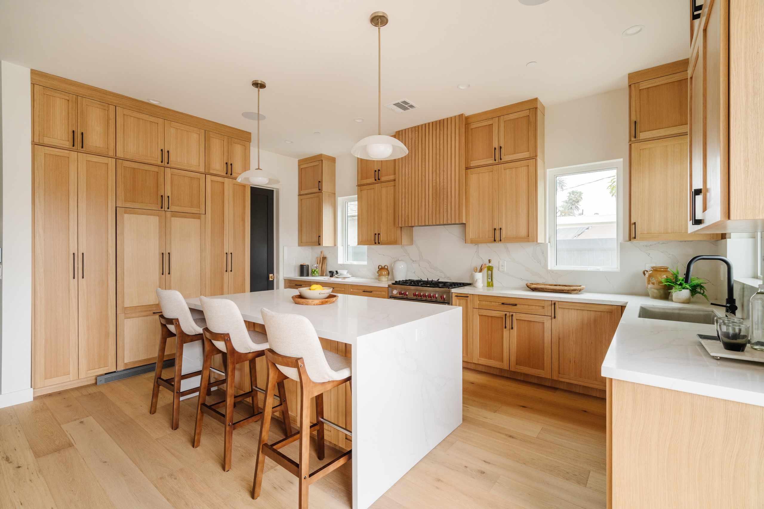 Modern kitchen with light wood cabinets and a white island.