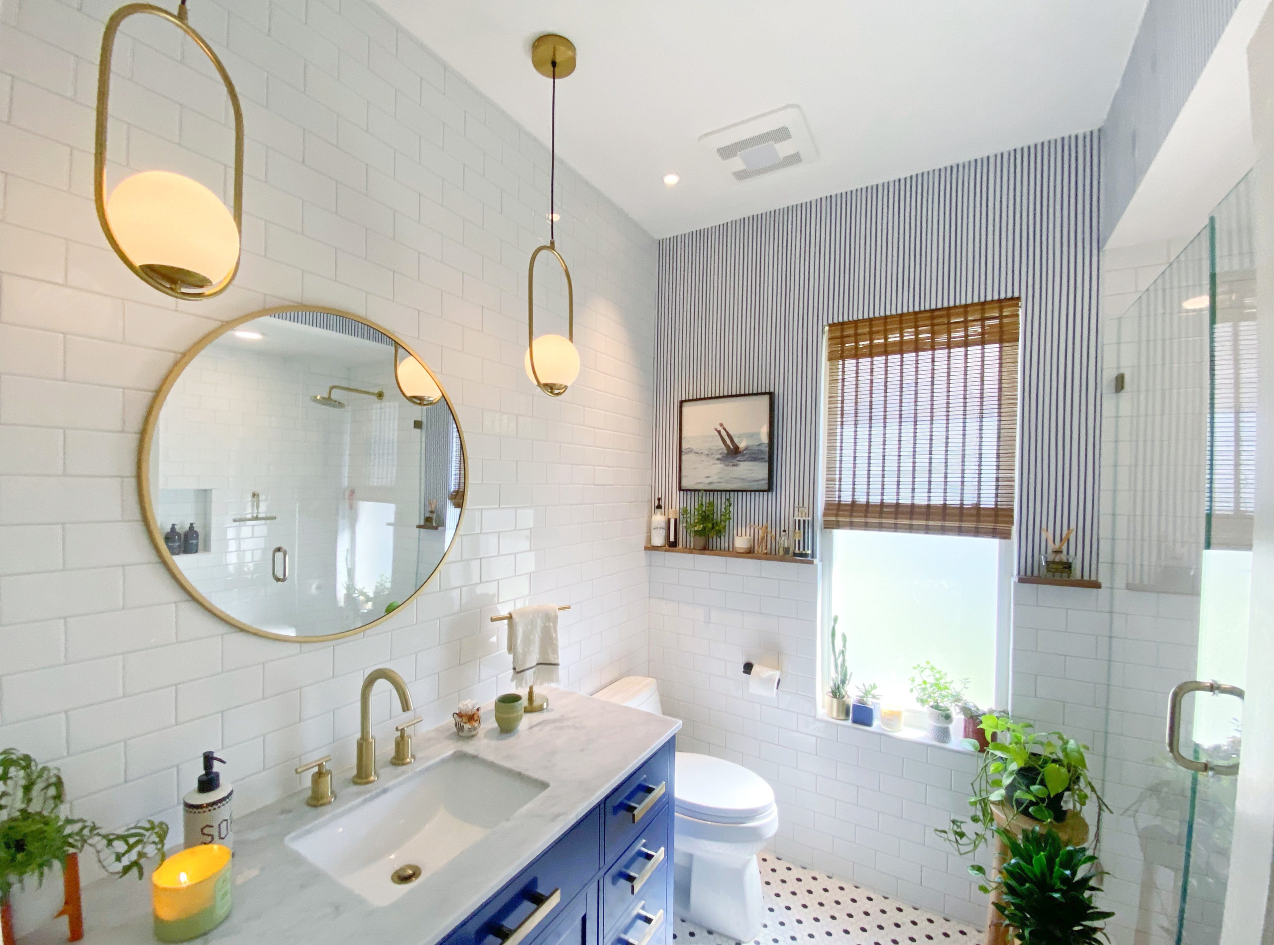 Stylish bathroom with blue vanity, round mirror, and gold fixtures.