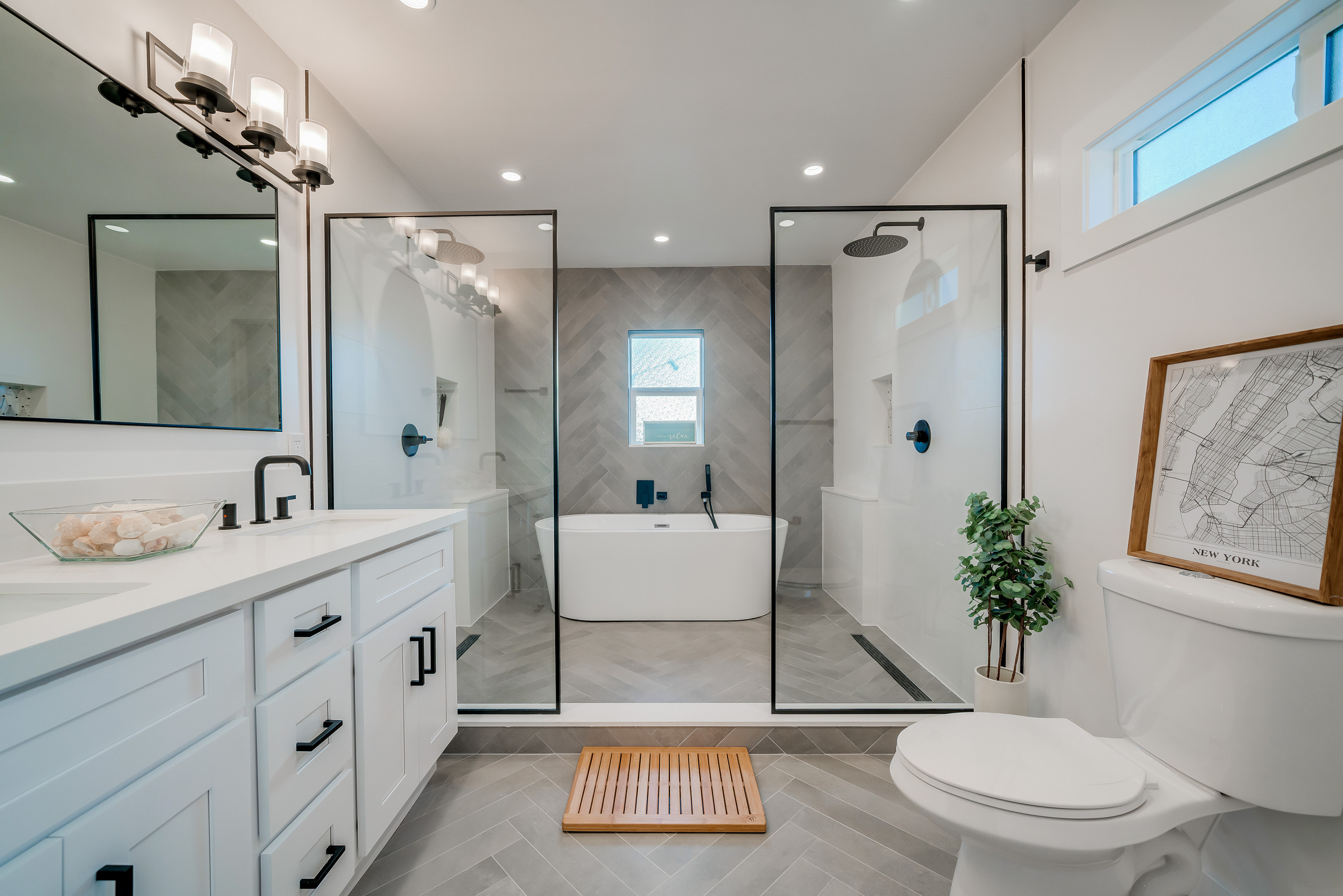Modern bathroom with dual glass showers, freestanding tub, and white vanity.