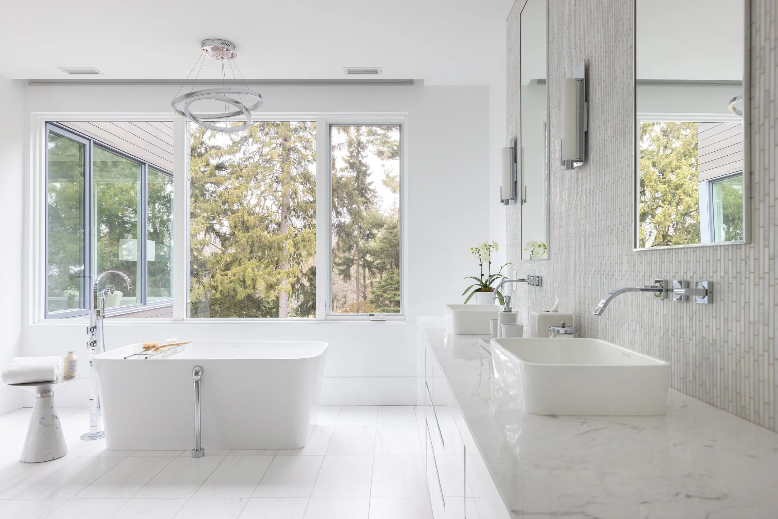 Minimalist white bathroom with freestanding tub and large windows.