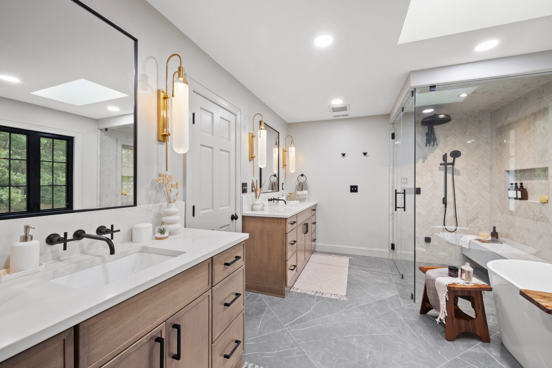 Luxury bathroom with double vanity, glass shower enclosure, modern lighting fixtures, and a freestanding bathtub.