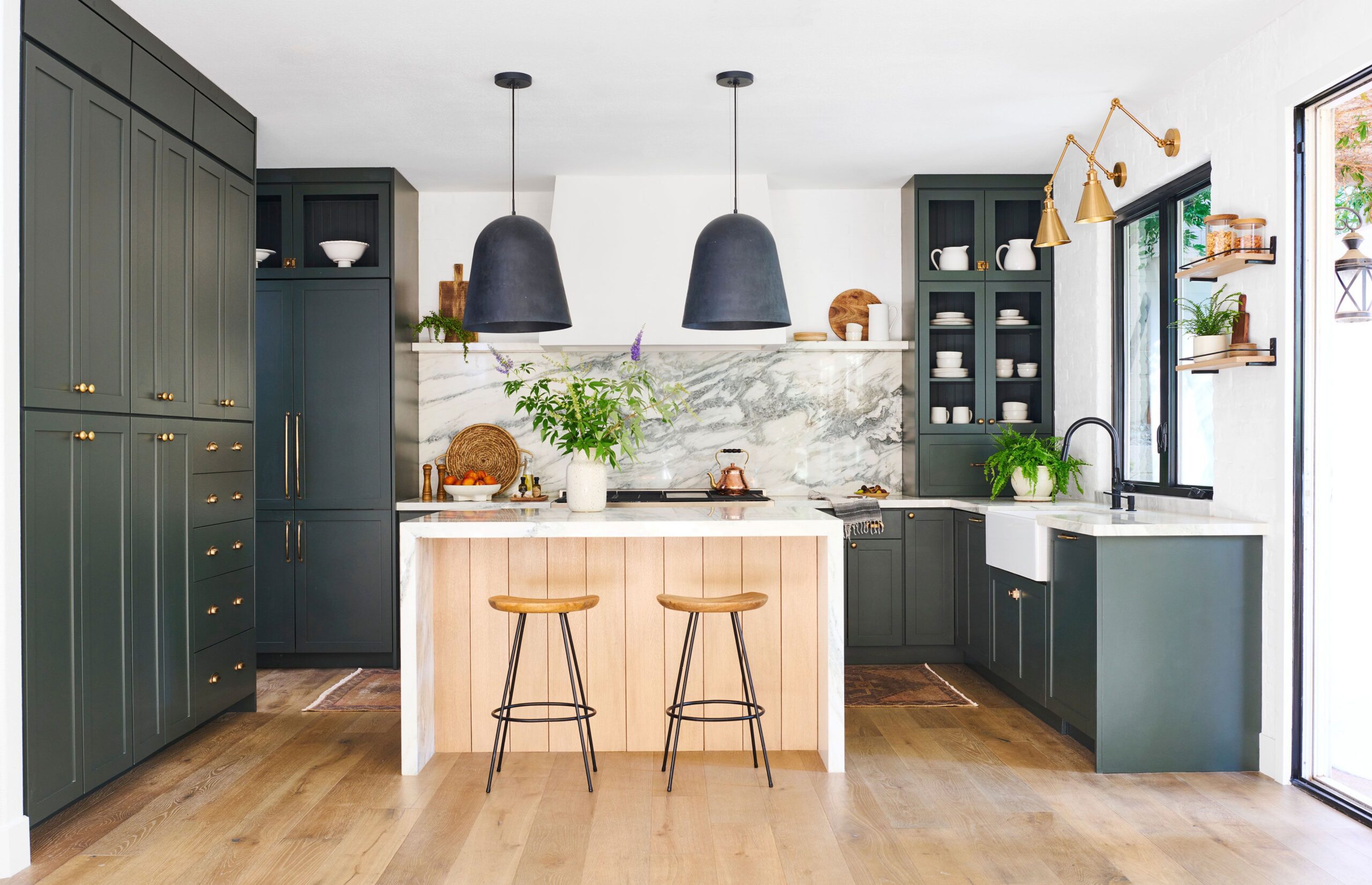 Modern kitchen with dark green cabinets and a marble backsplash.