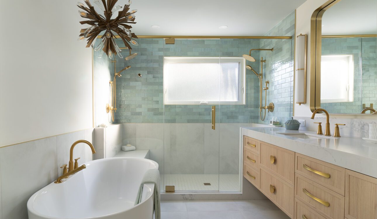 Luxurious bathroom with freestanding bathtub, glass shower, green tiles, and gold fixtures.