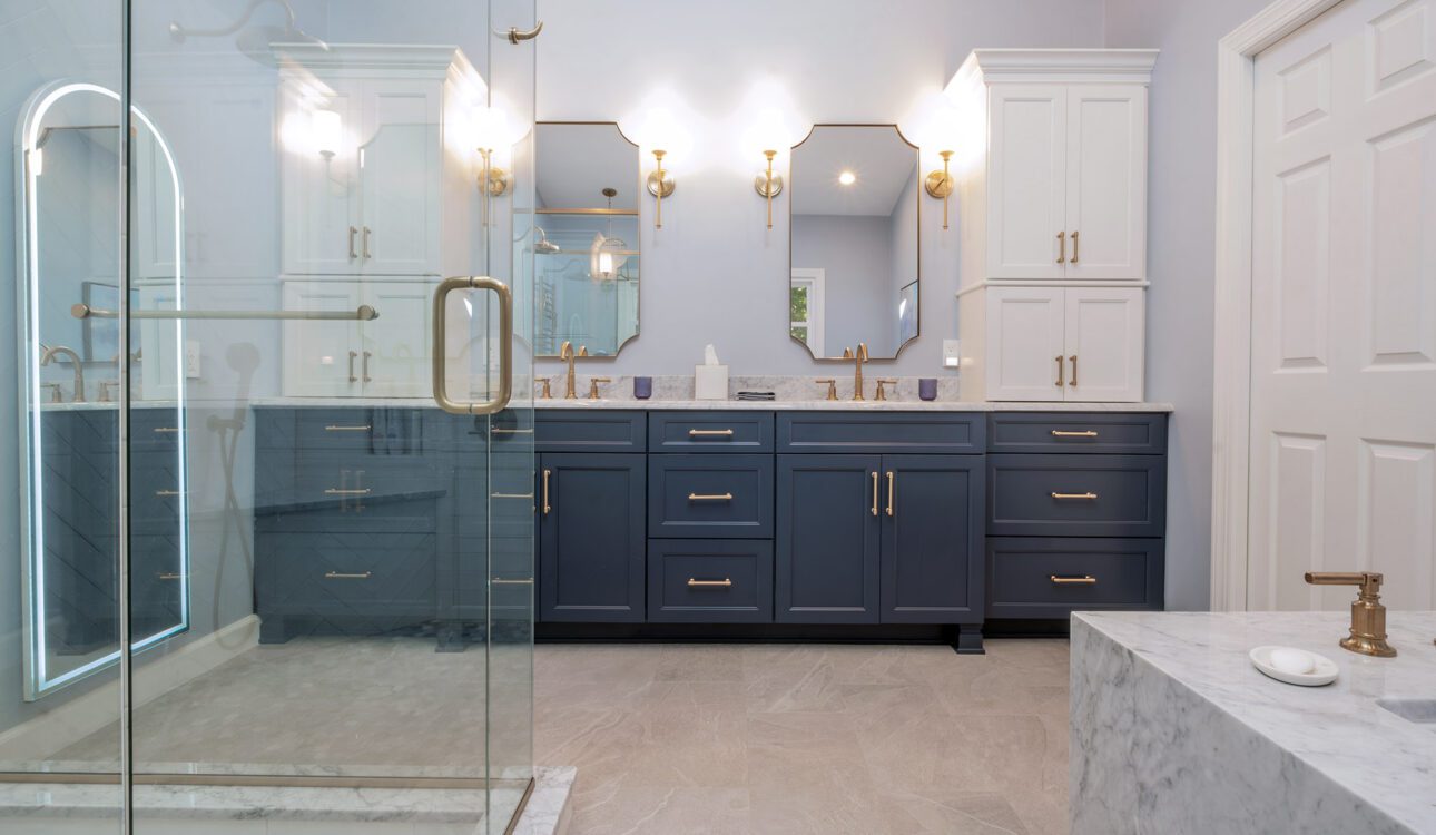 Elegant bathroom with navy blue vanity, marble countertops, and glass shower enclosure