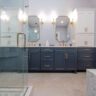 Elegant bathroom with navy blue vanity, marble countertops, and glass shower enclosure