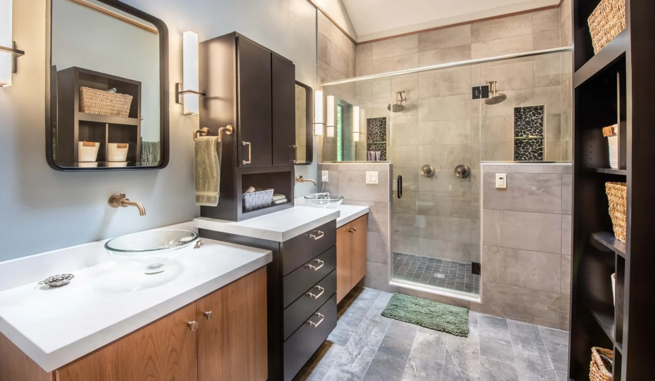 Contemporary bathroom with dual sinks, glass vessel basins, glass shower enclosure, and modern wood cabinetry.