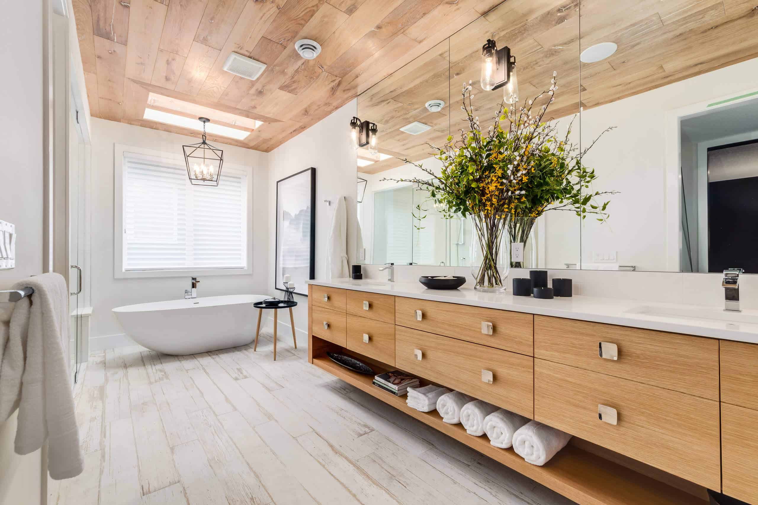 Modern bathroom with wooden ceiling, large vanity, and freestanding bathtub.