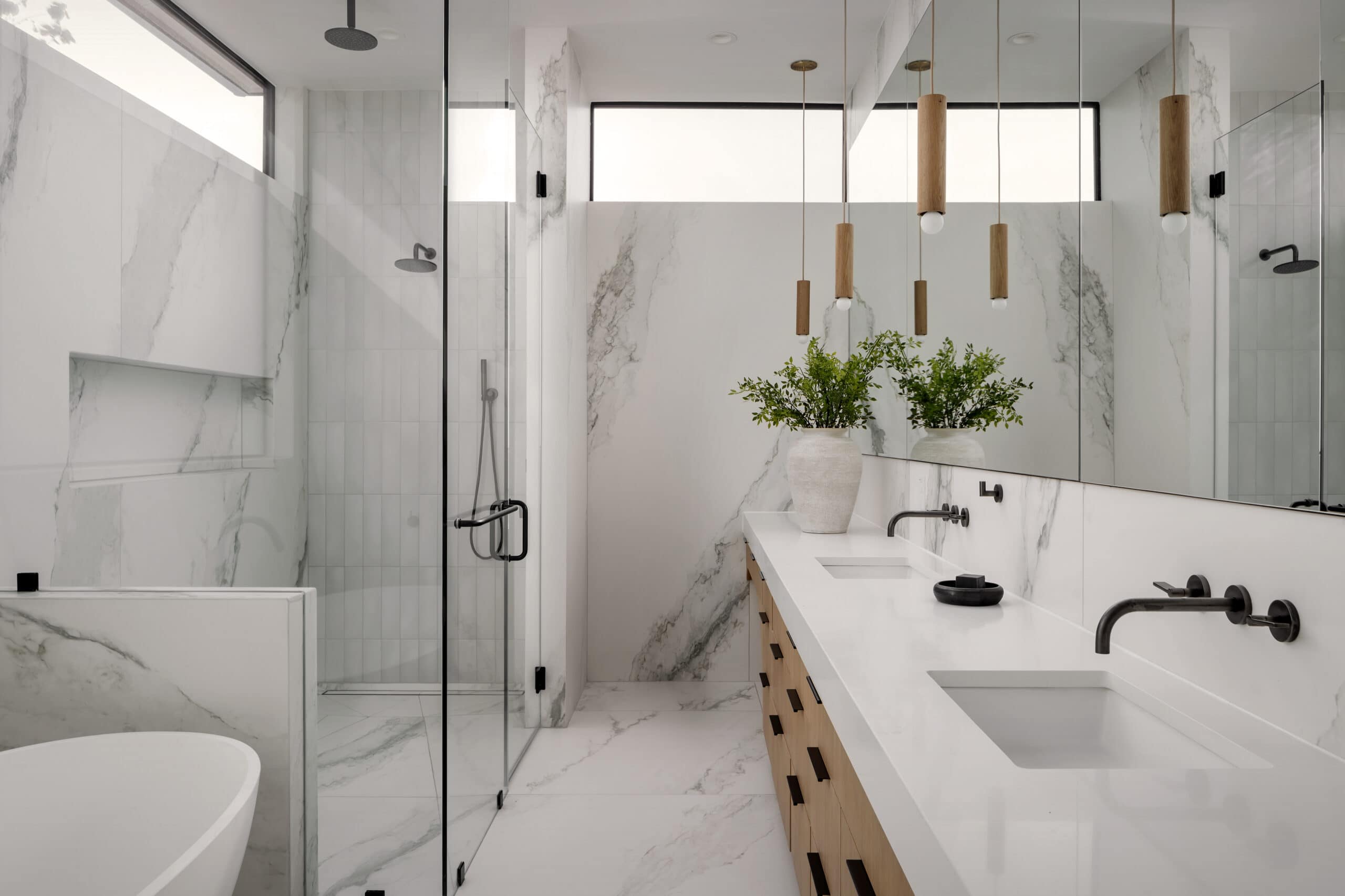 Luxurious modern bathroom with glass shower, freestanding tub, and double vanity with wall-mounted faucets.