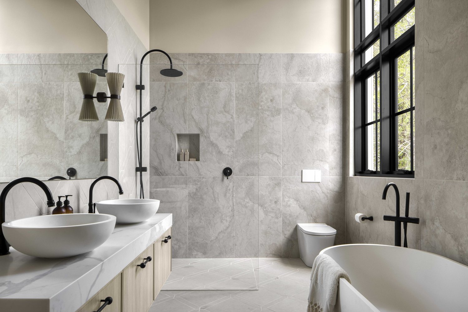 Modern luxury bathroom with freestanding tub, dual vessel sinks, walk-in shower, and large window.