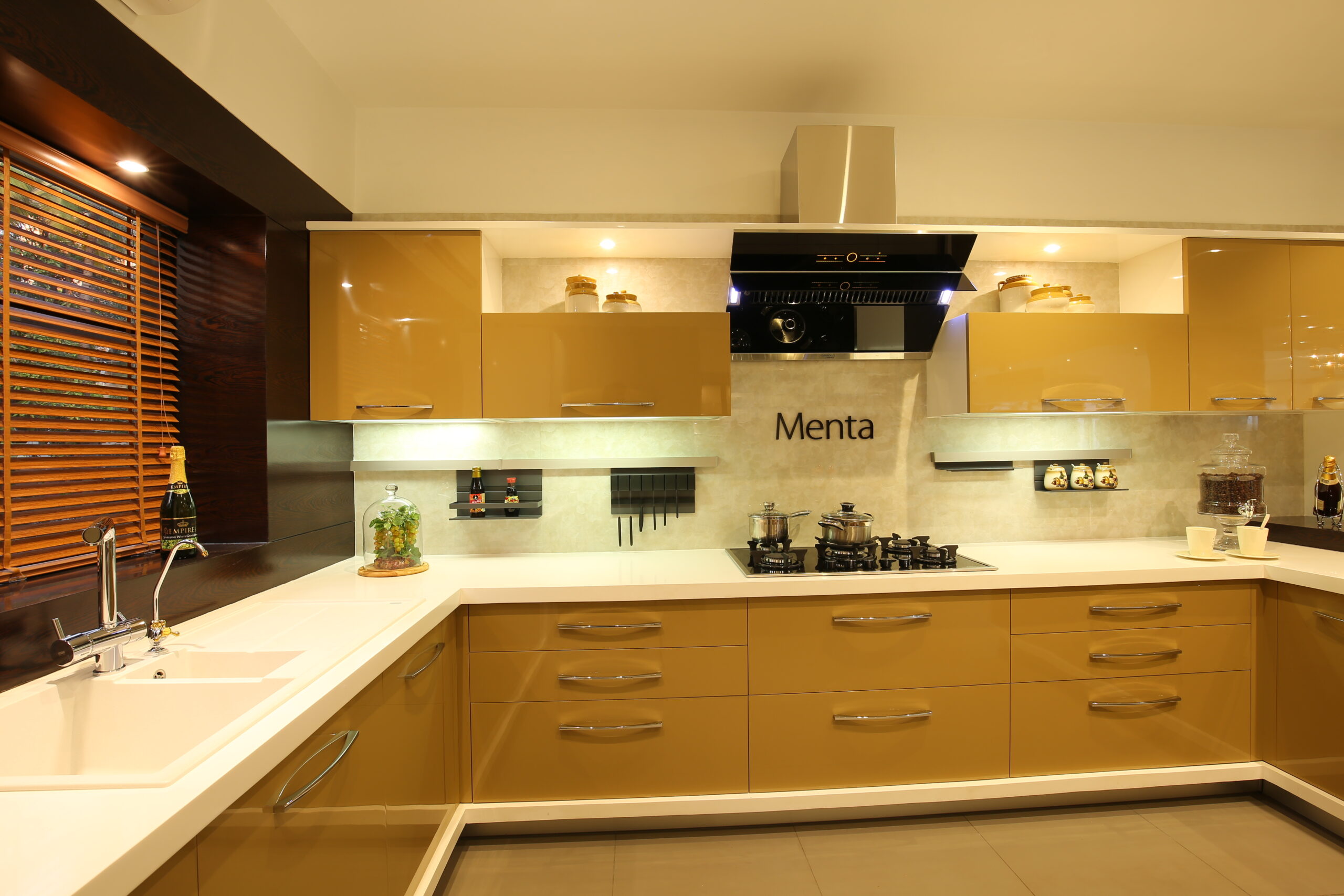 Modern U-shaped kitchen with glossy mustard yellow cabinets, white countertops, under-cabinet lighting, and a sleek black chimney hood.