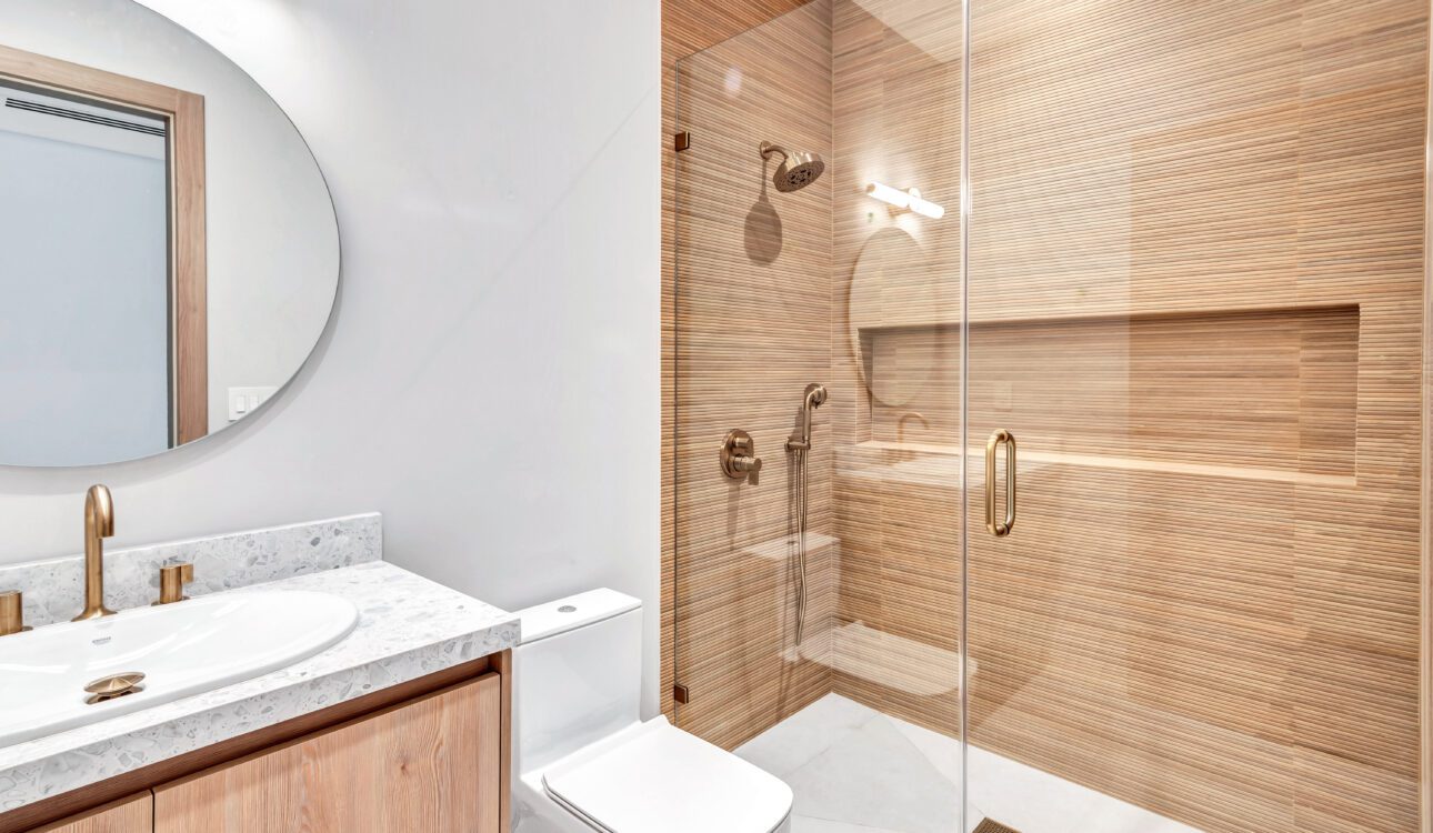 Modern bathroom with wood accents and glass shower enclosure.
