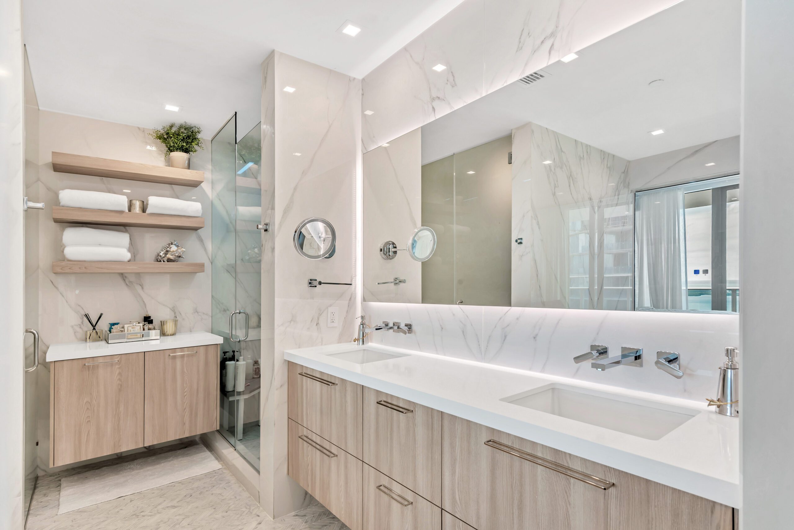 Modern bathroom with double vanity, large mirror, and glass shower.