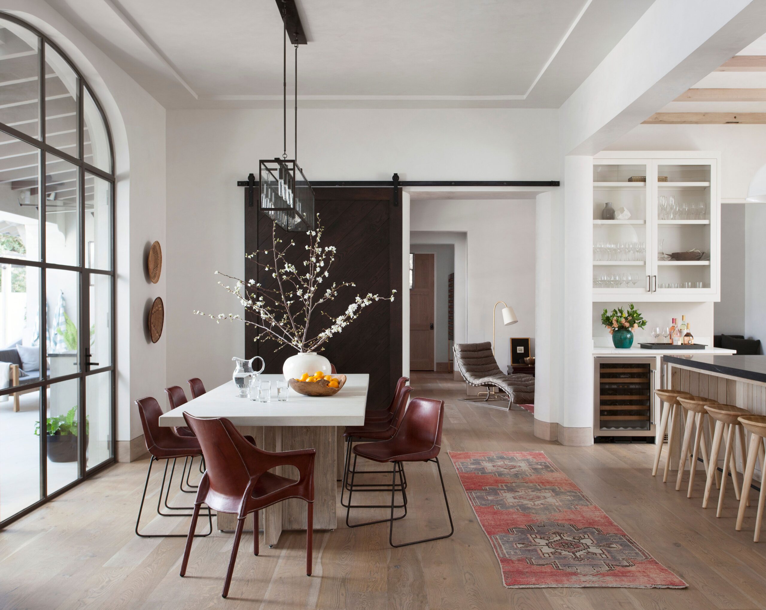 Elegant open-concept dining and kitchen area with natural light, modern furniture, and rustic touches.