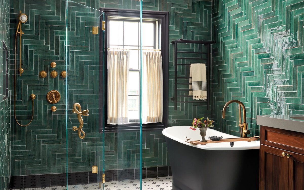 Elegant bathroom with green herringbone tile walls and gold fixtures.