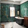Elegant bathroom with green herringbone tile walls and gold fixtures.