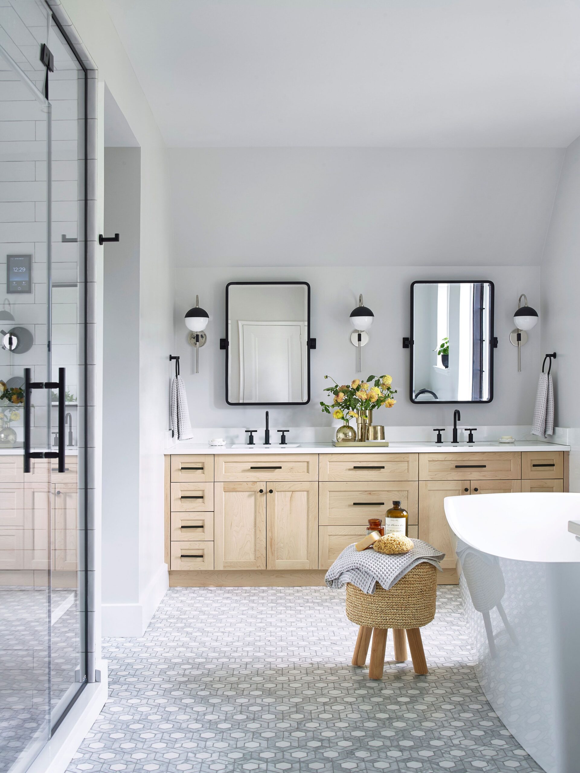Modern bathroom with glass shower, double vanity, freestanding tub, and patterned floor tiles.