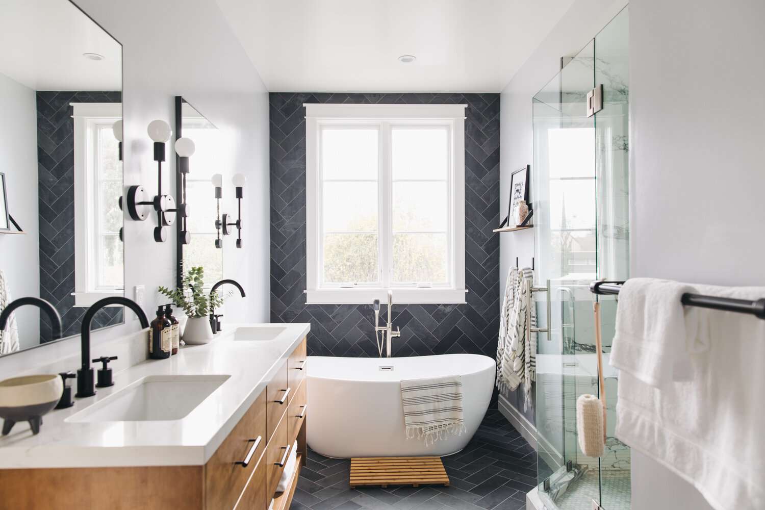 Modern bathroom with black tile accent wall and freestanding tub