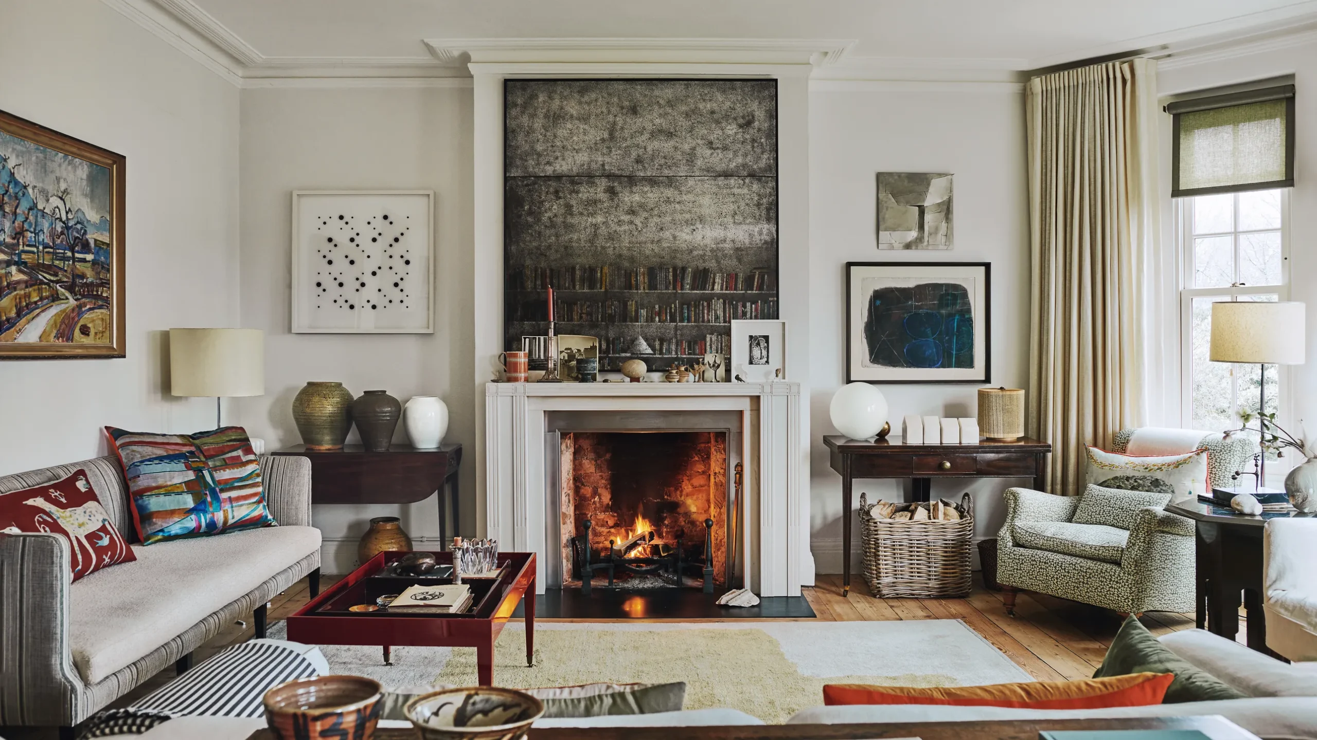Warm living room with fireplace, eclectic decor, artwork, and layered textiles