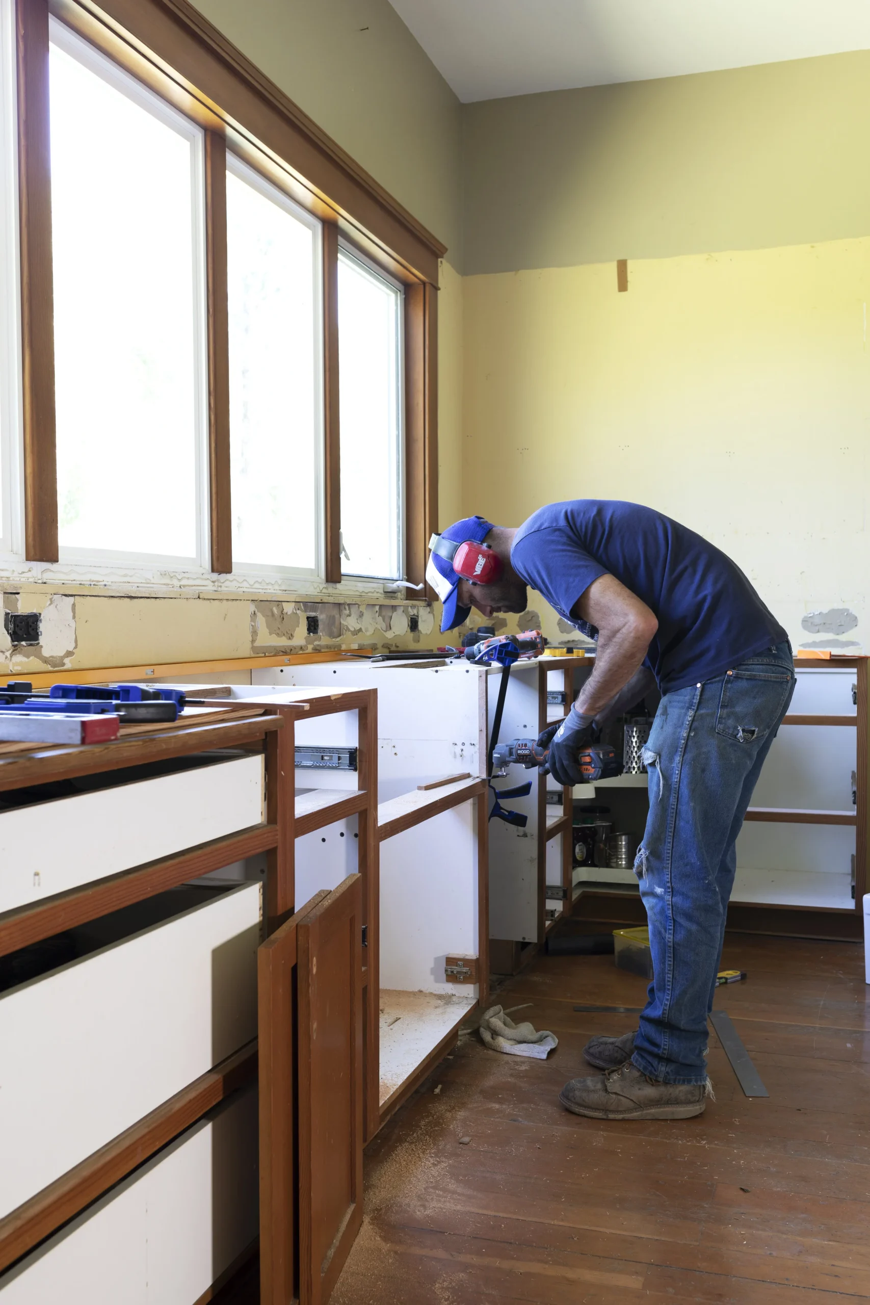 Worker installing lower kitchen cabinets during a kitchen renovation.