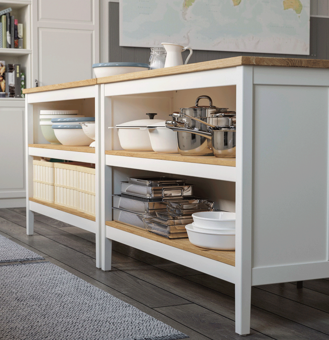 A white kitchen island with natural wood countertop featuring open shelves filled with neatly stacked bowls, pots, and glass containers, set on a dark wood floor.