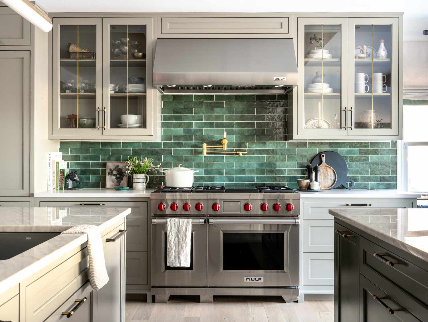 Kitchen featuring a striking green subway tile backsplash, stainless steel range, glass-front cabinets, and marble countertops.