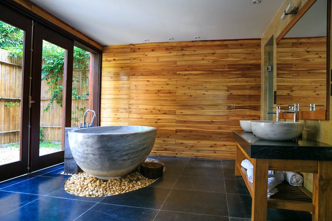  Luxurious bathroom with a marble bathtub, wooden walls, and a double sink vanity