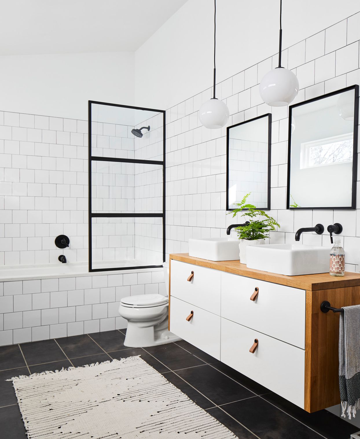 Modern bathroom with white subway tiles, wooden vanity, and black accents.