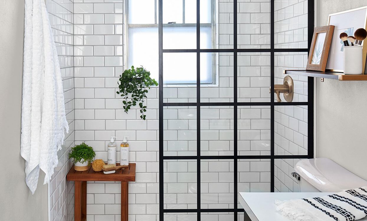 Modern small bathroom with black framed shower, white subway tiles, and patterned floor.