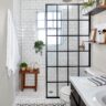 Stylish black and white bathroom with patterned floor tiles and a glass shower divider