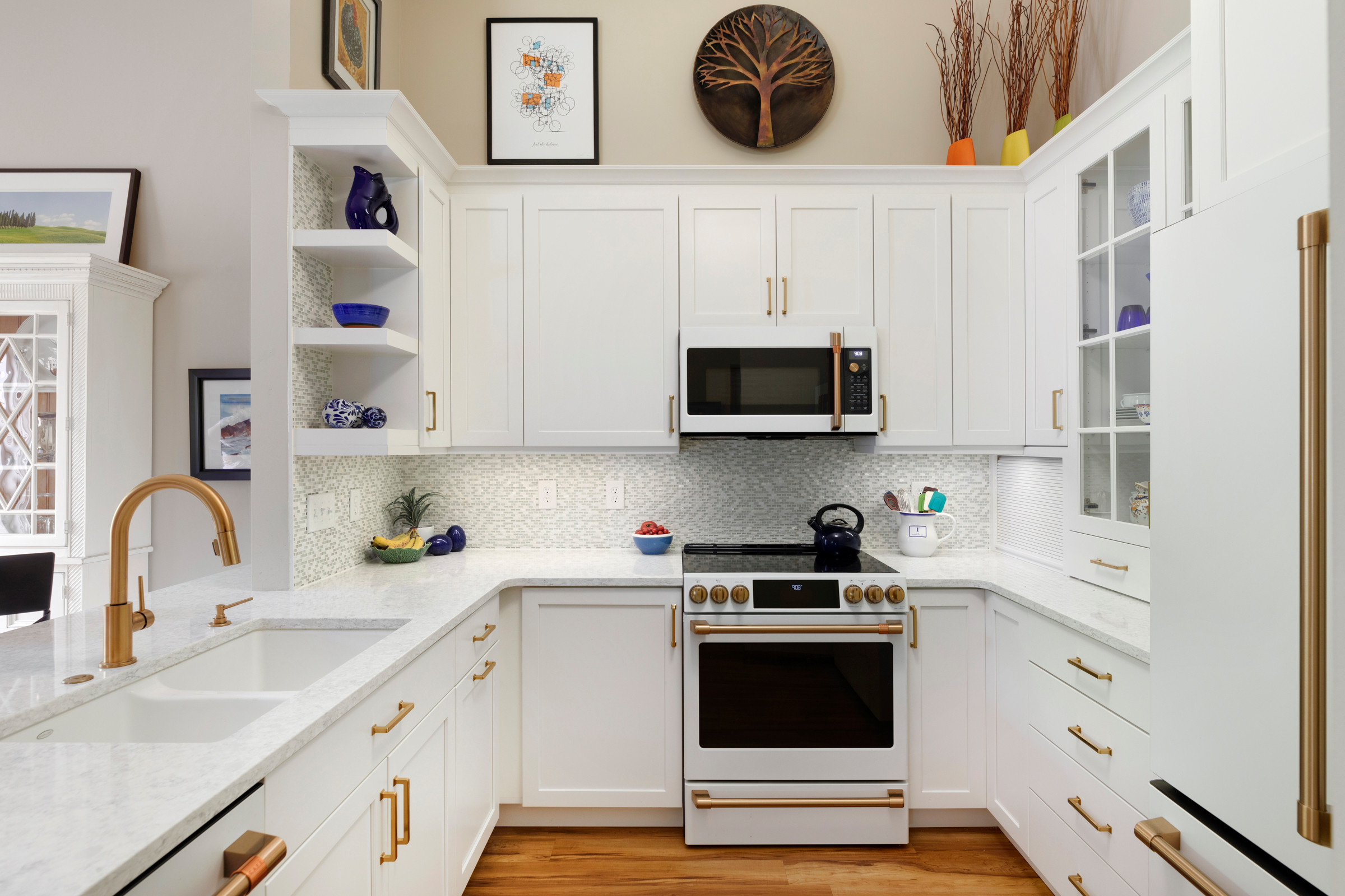 Modern white kitchen with gold hardware and built-in appliances.