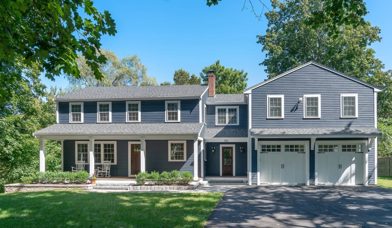 Fully remodeled two-story blue house with white trim, attached two-car garage, and front porch.