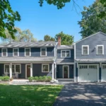 Fully remodeled two-story blue house with white trim, attached two-car garage, and front porch.