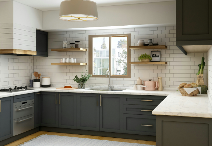 Stylish kitchen featuring gray lower cabinets with brass hardware, white subway tile backsplash, wood floating shelves, and marble countertops.