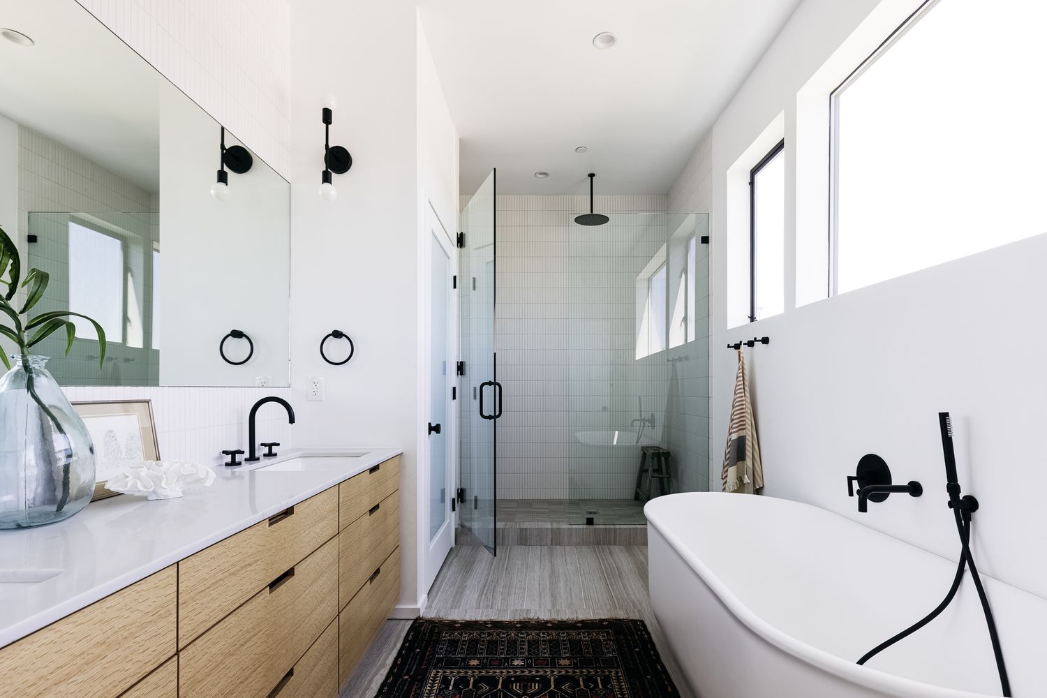 Minimalist bathroom with freestanding tub, glass shower, and wooden vanity.