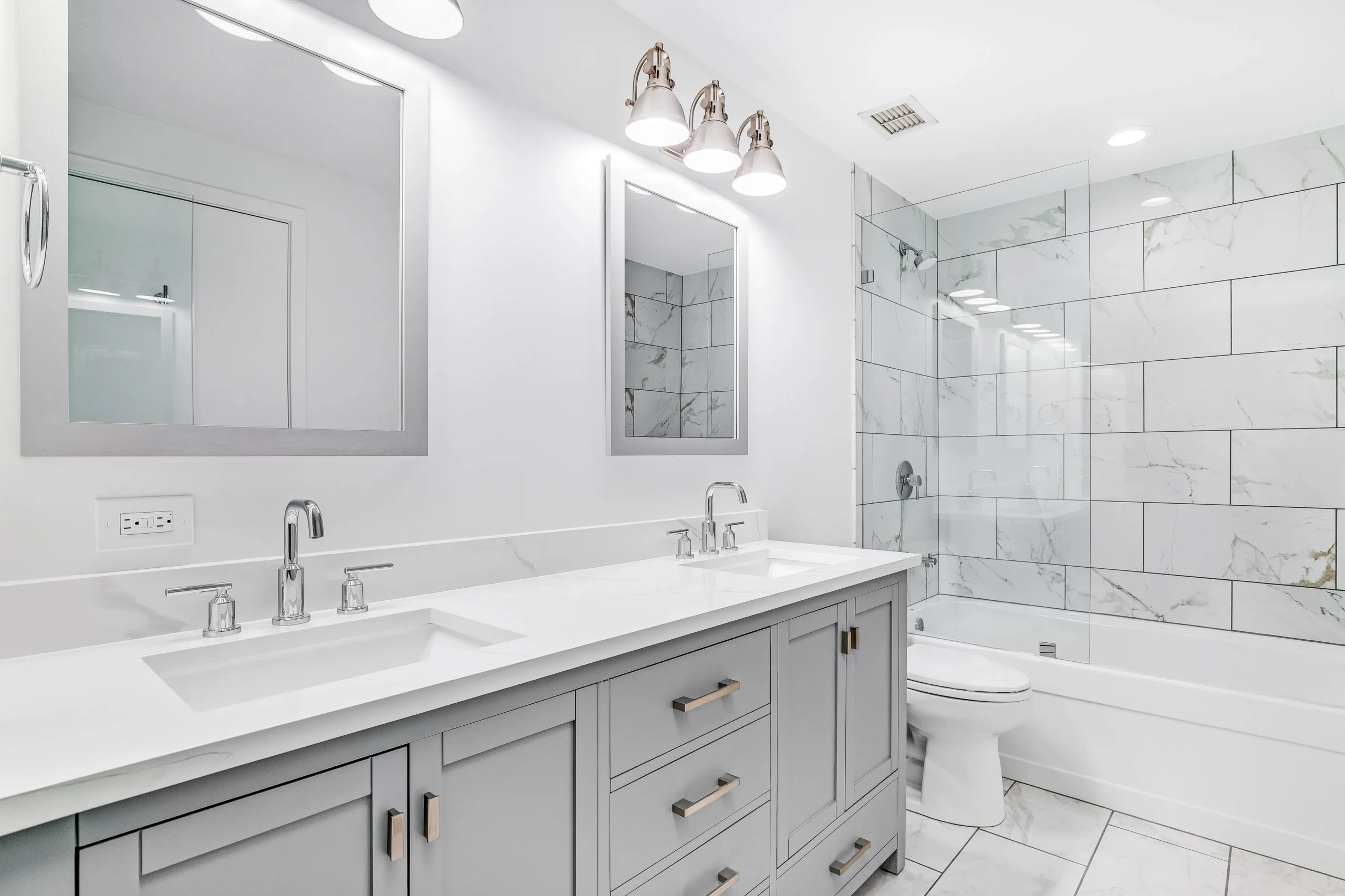 Modern bathroom with double vanity, marble tile shower, and sleek chrome fixtures.